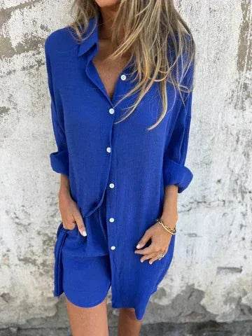 Woman wearing a trendy blue button-up shirt dress from ZA-Zola, standing by a textured wall.