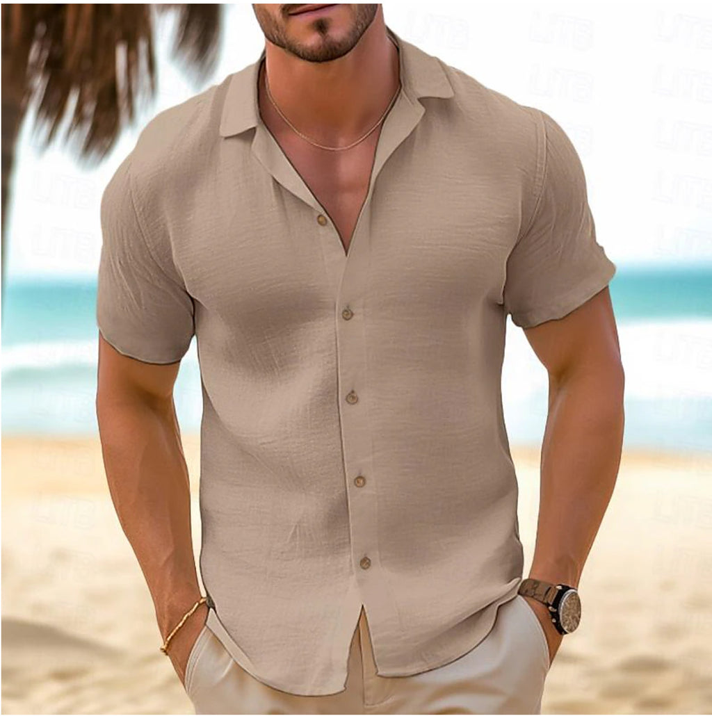 Man wearing a beige shirt on a beach with palm trees and ocean in the background