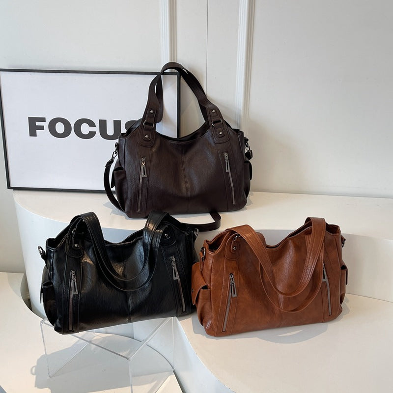 Three handbags in black, brown, and another color on a white surface with a 'FOCUS' sign in the background.
