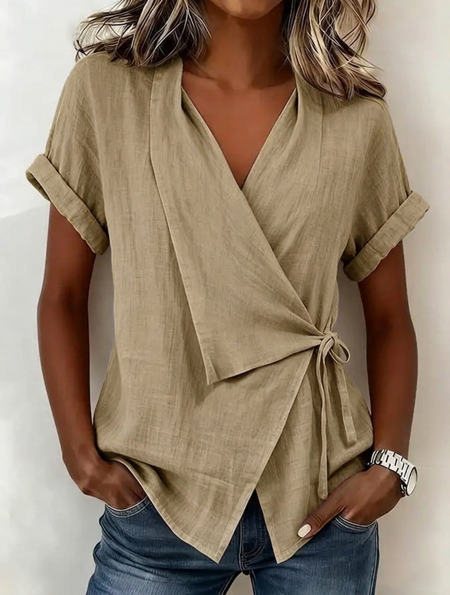 Woman wearing a beige wrap top with short sleeves against a white background