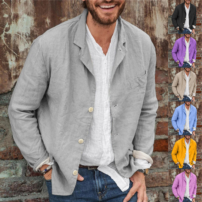 Man wearing a light gray jacket over a white shirt with a brick wall background