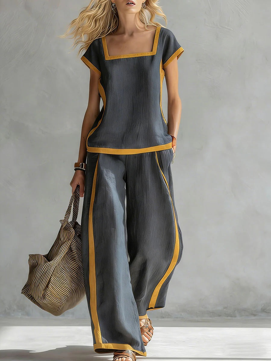 Woman wearing a gray outfit with yellow accents, holding a textured bag against a neutral background