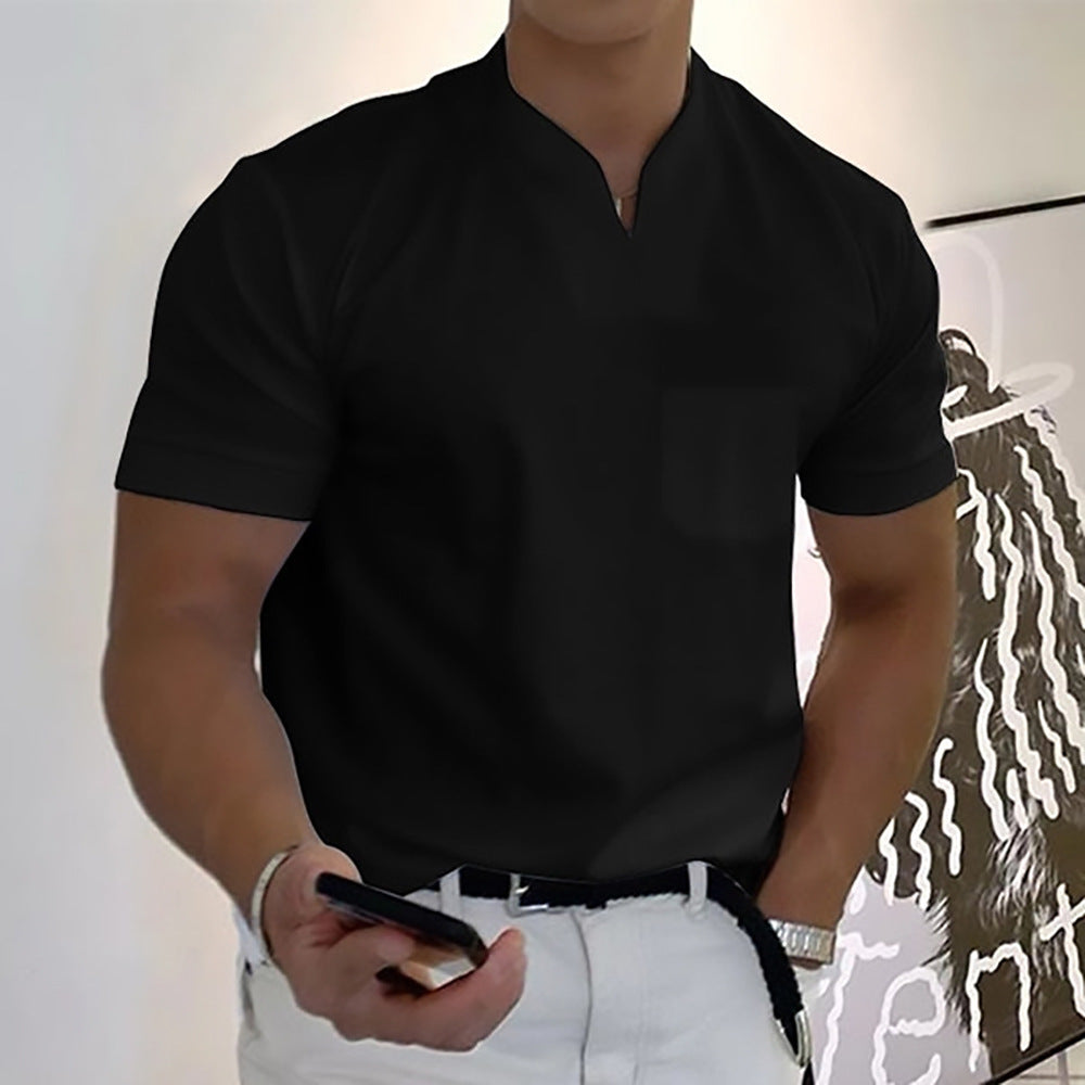 Person wearing a black shirt and white pants holding a phone against a plain background