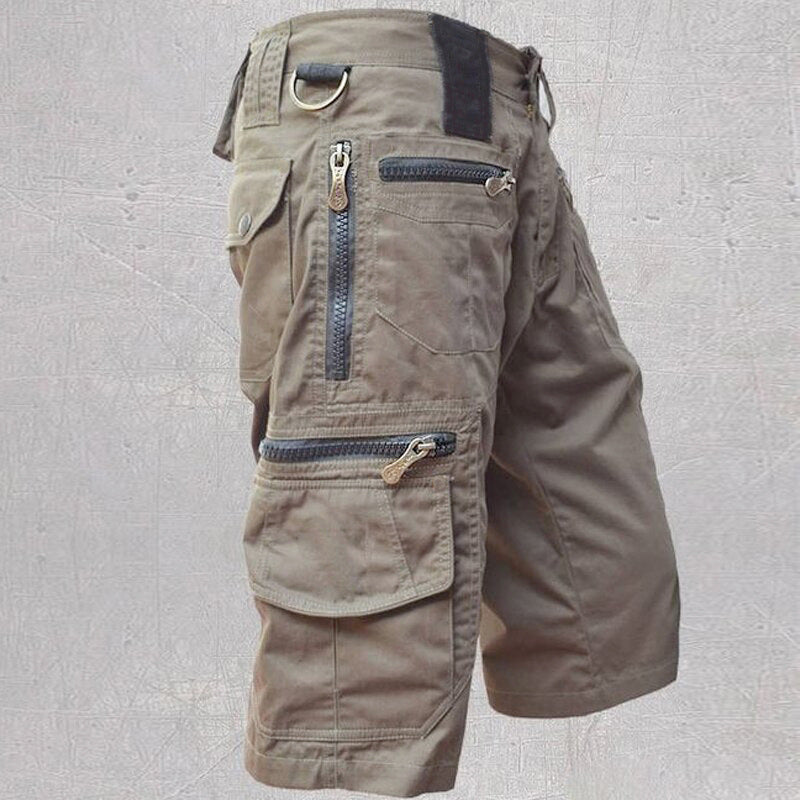 Brown cargo shorts with multiple pockets and zippers on a textured gray background