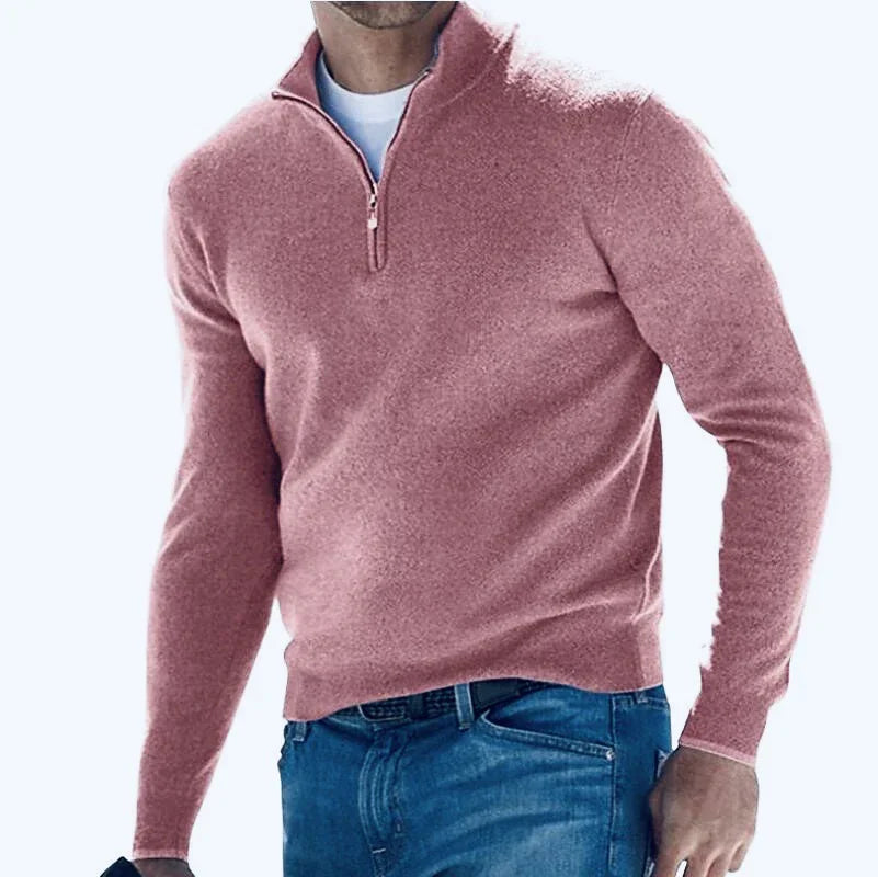 Man wearing a pink half-zip sweater and blue jeans on a white background