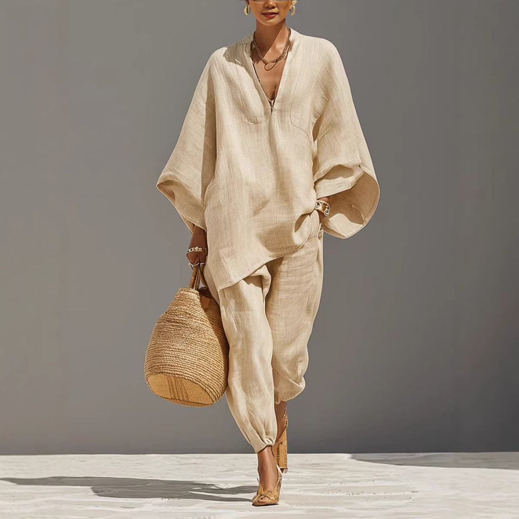 Woman in a beige outfit holding a woven bag against a neutral background