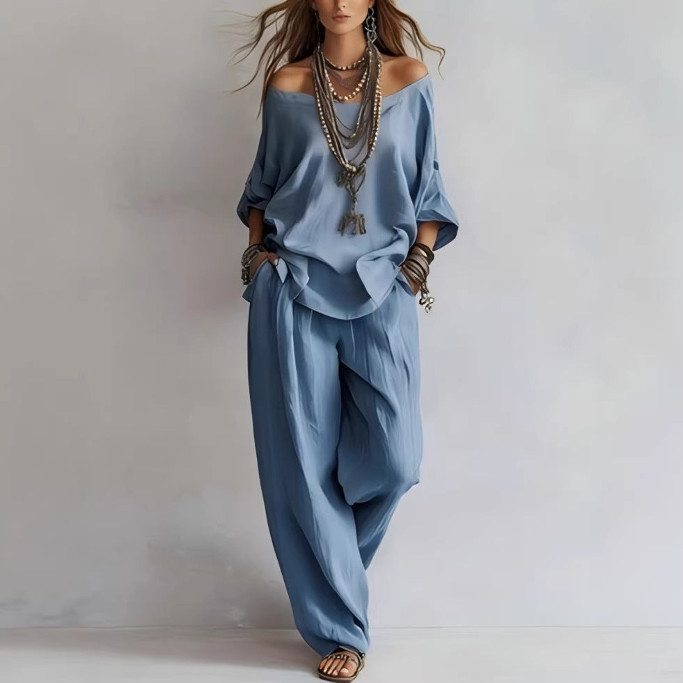 Woman wearing a blue outfit with wide-leg pants and off-shoulder top on a plain background