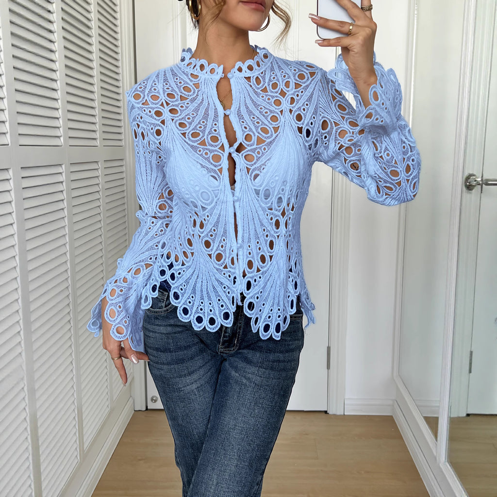 Person wearing a light blue lace top and jeans in a room with white walls.