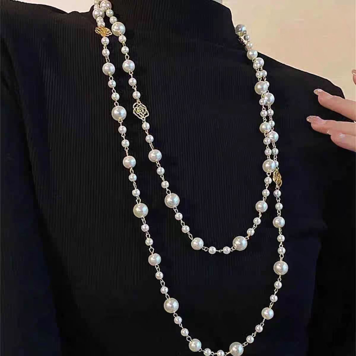 Long pearl necklace draped over a black garment