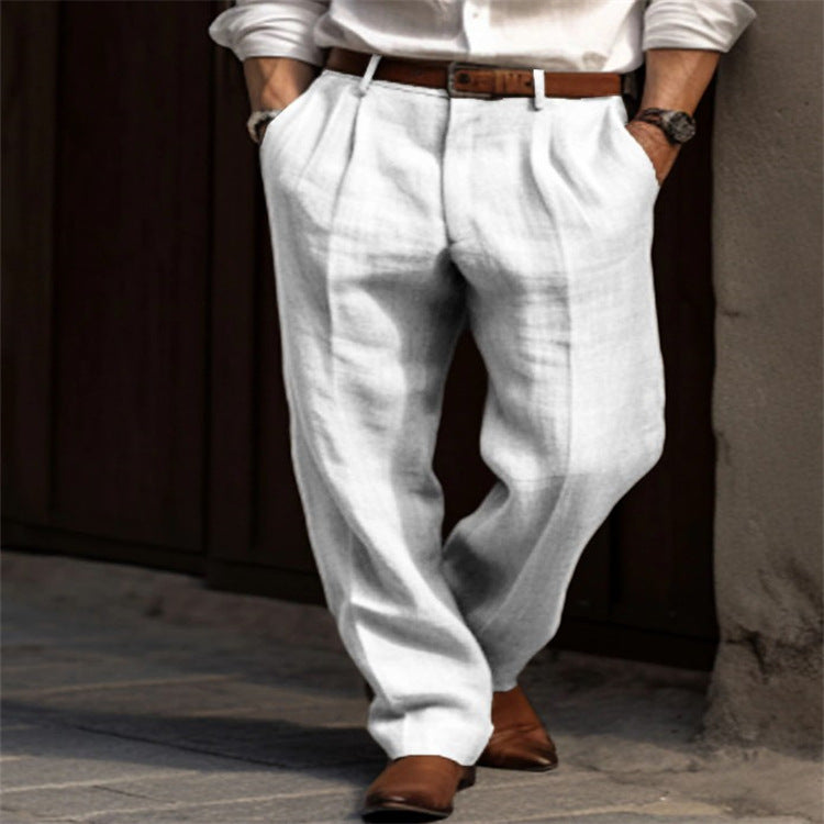Person wearing white pants and a white shirt with brown shoes and belt, standing against a dark background.