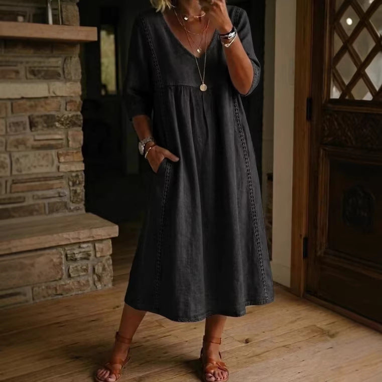 Person wearing a dark gray dress standing in a room with wooden flooring and a stone fireplace.