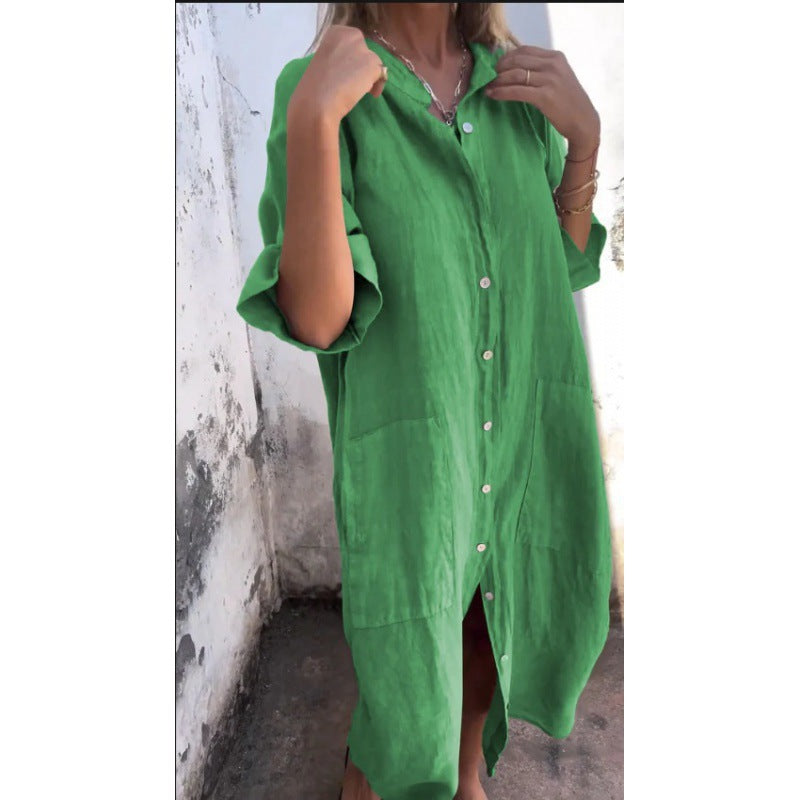 Green dress with button details worn by a person against a white wall.