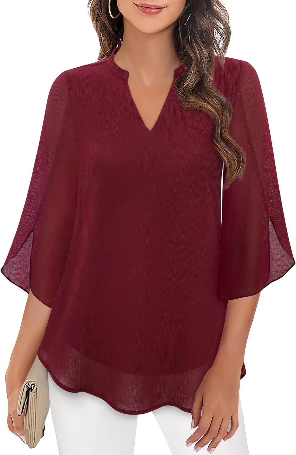 Woman wearing a burgundy blouse with sheer sleeves on a white background