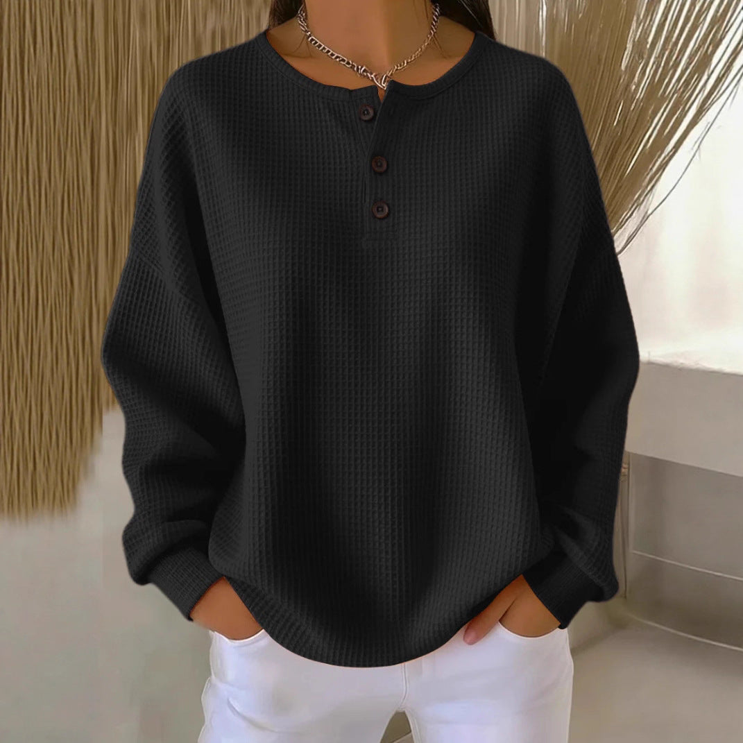 Person wearing a black sweater and white pants with a neutral background