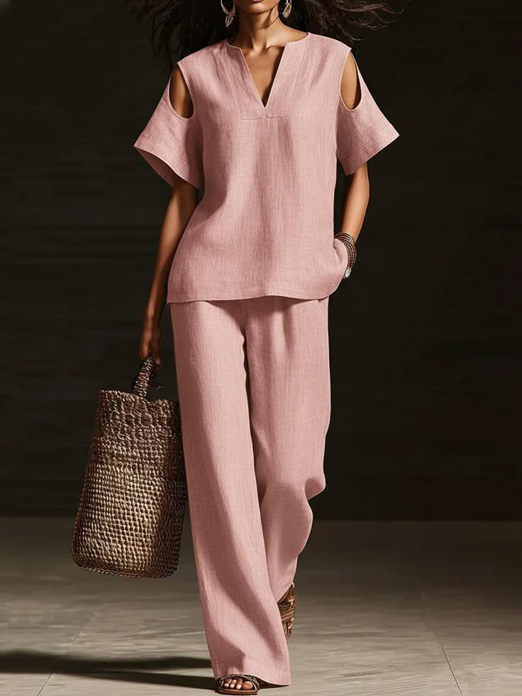 Woman wearing a pink outfit with a straw bag against a dark background