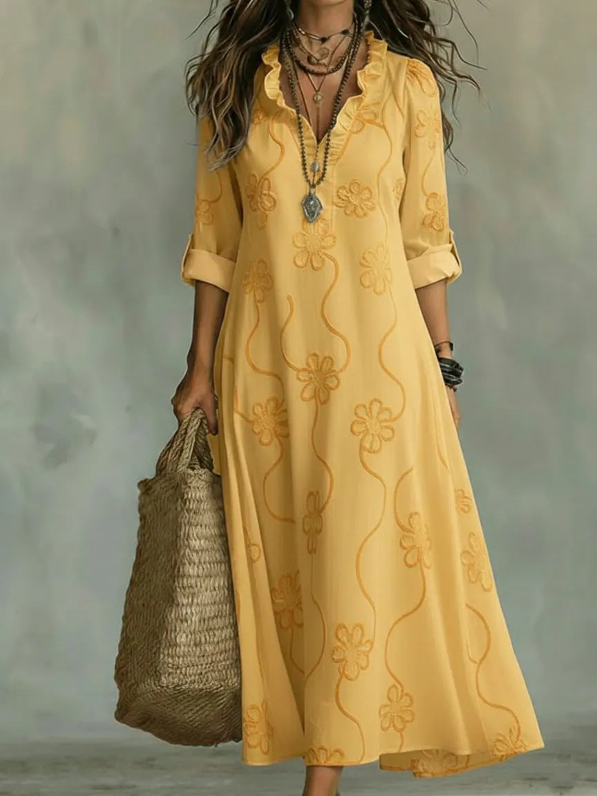 Woman wearing a yellow embroidered dress holding a woven bag against a neutral background