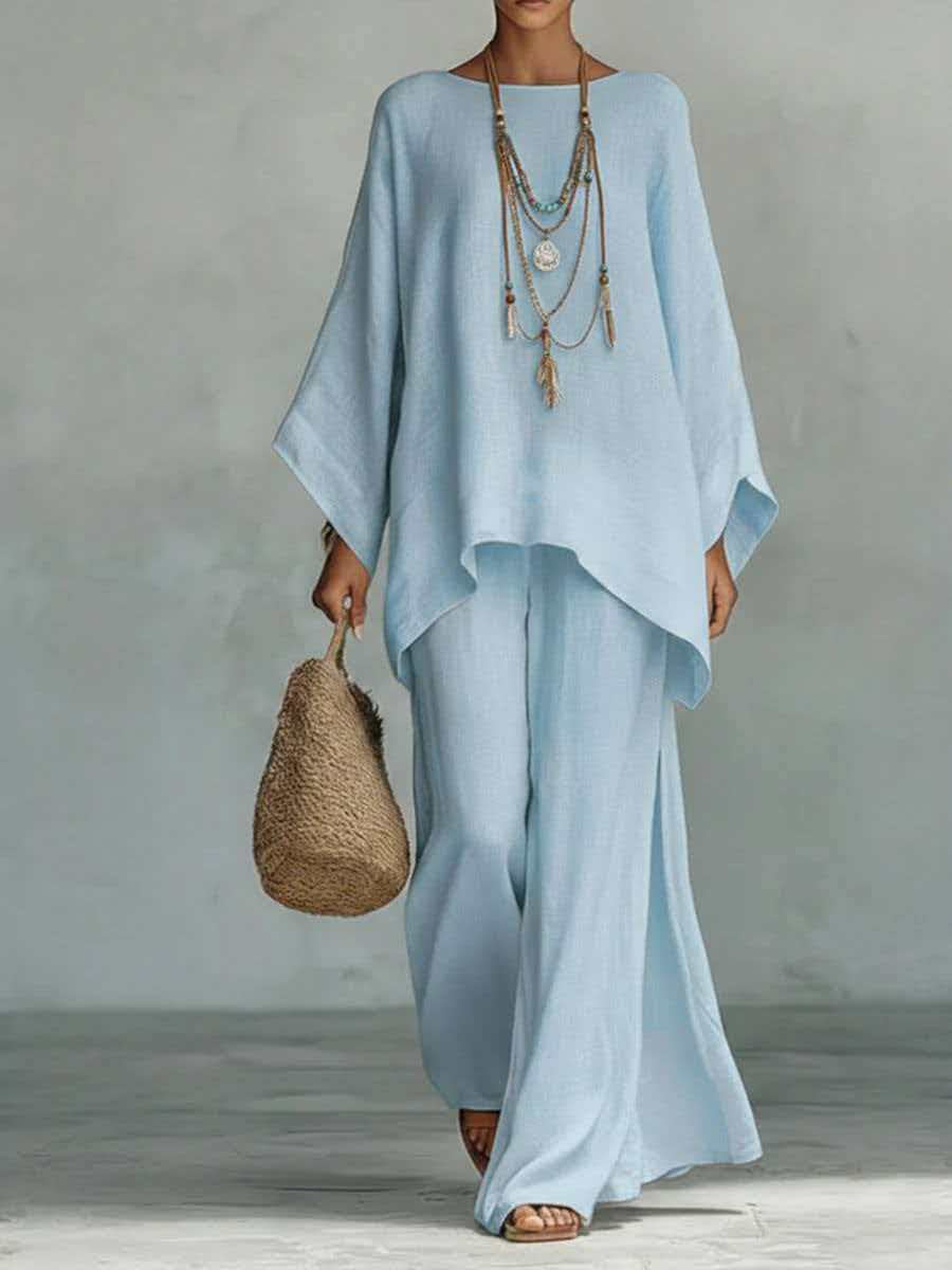 Woman wearing a light blue dress holding a woven bag against a neutral background