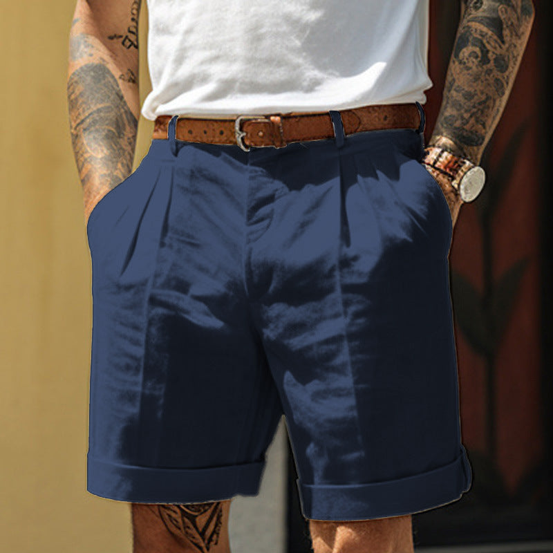 Person wearing navy shorts with a white shirt and tattooed arms.