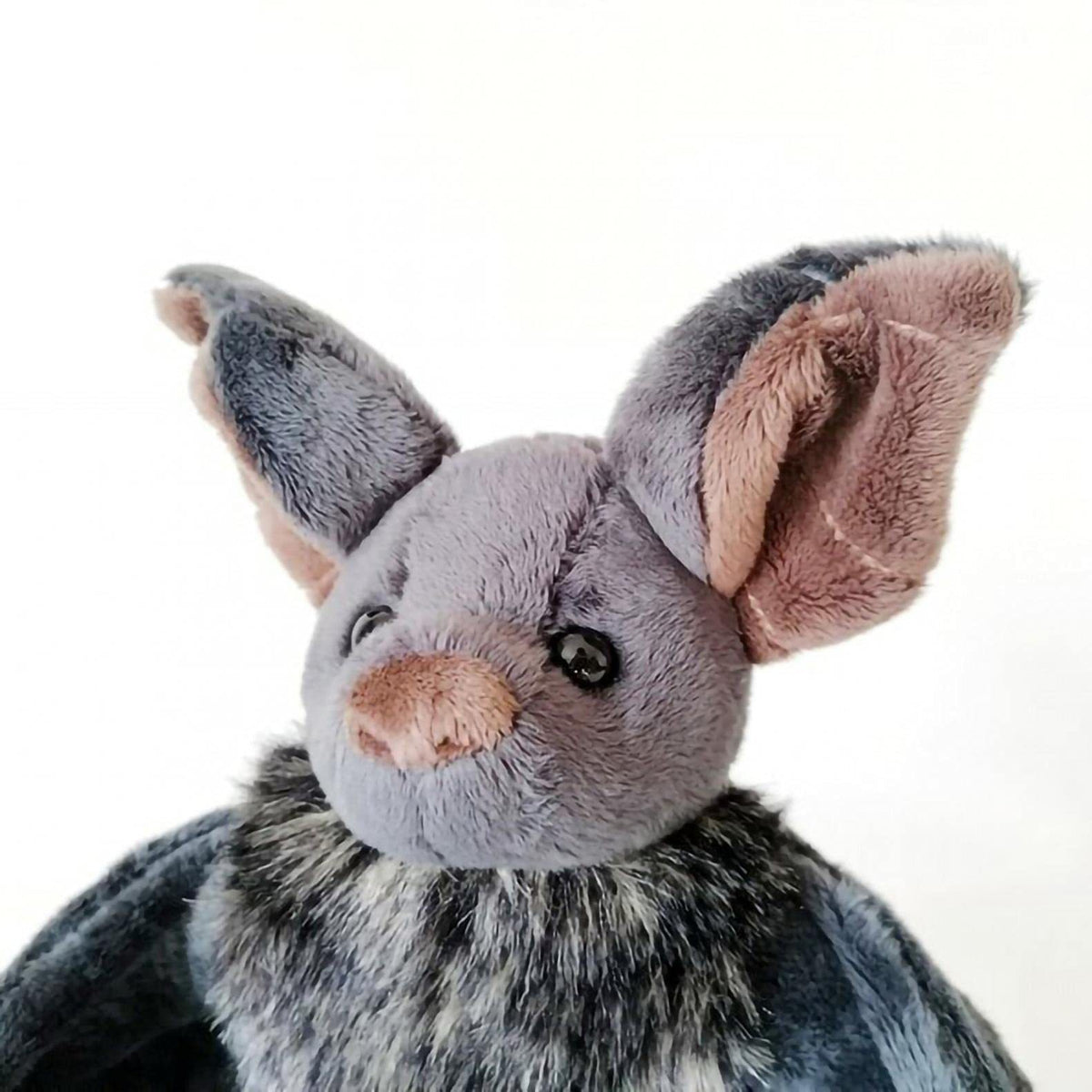 Plush toy bat with gray fur and pink ears on a white background