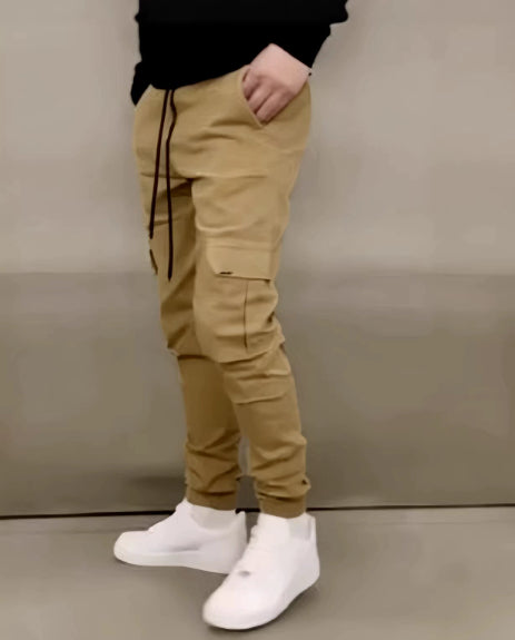Person wearing beige jogger pants and white sneakers against a plain background