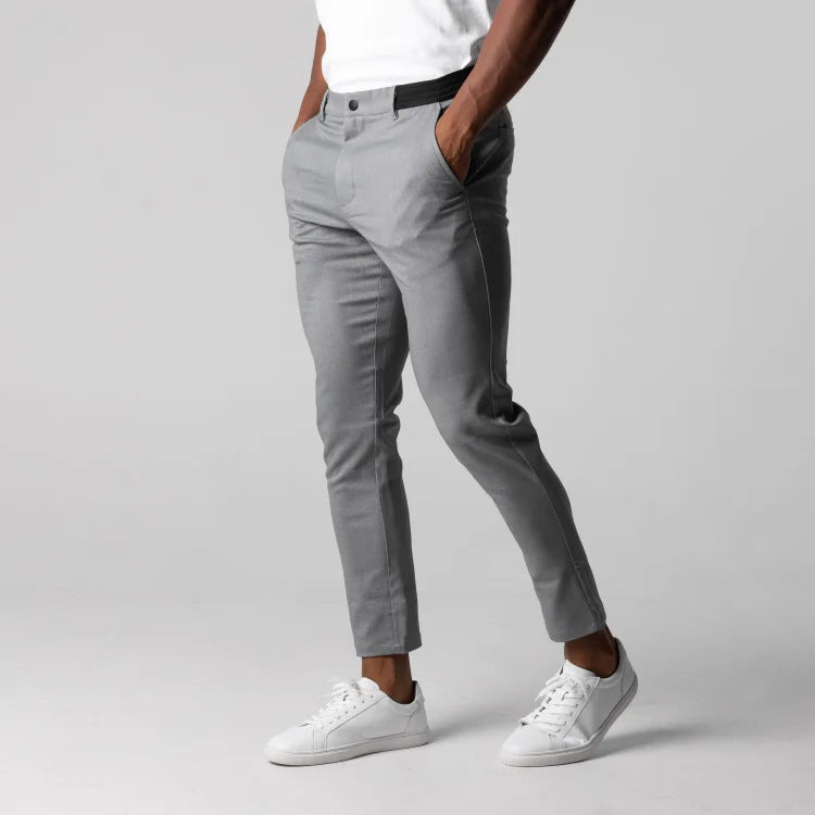 Person wearing gray pants and white sneakers on a plain background