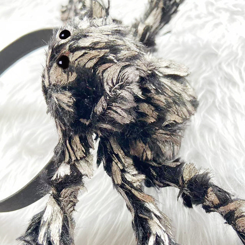A close-up of a furry monster toy with black and gray matted fur, large black eyes, and a curved black claw, lying on a white textured surface.
