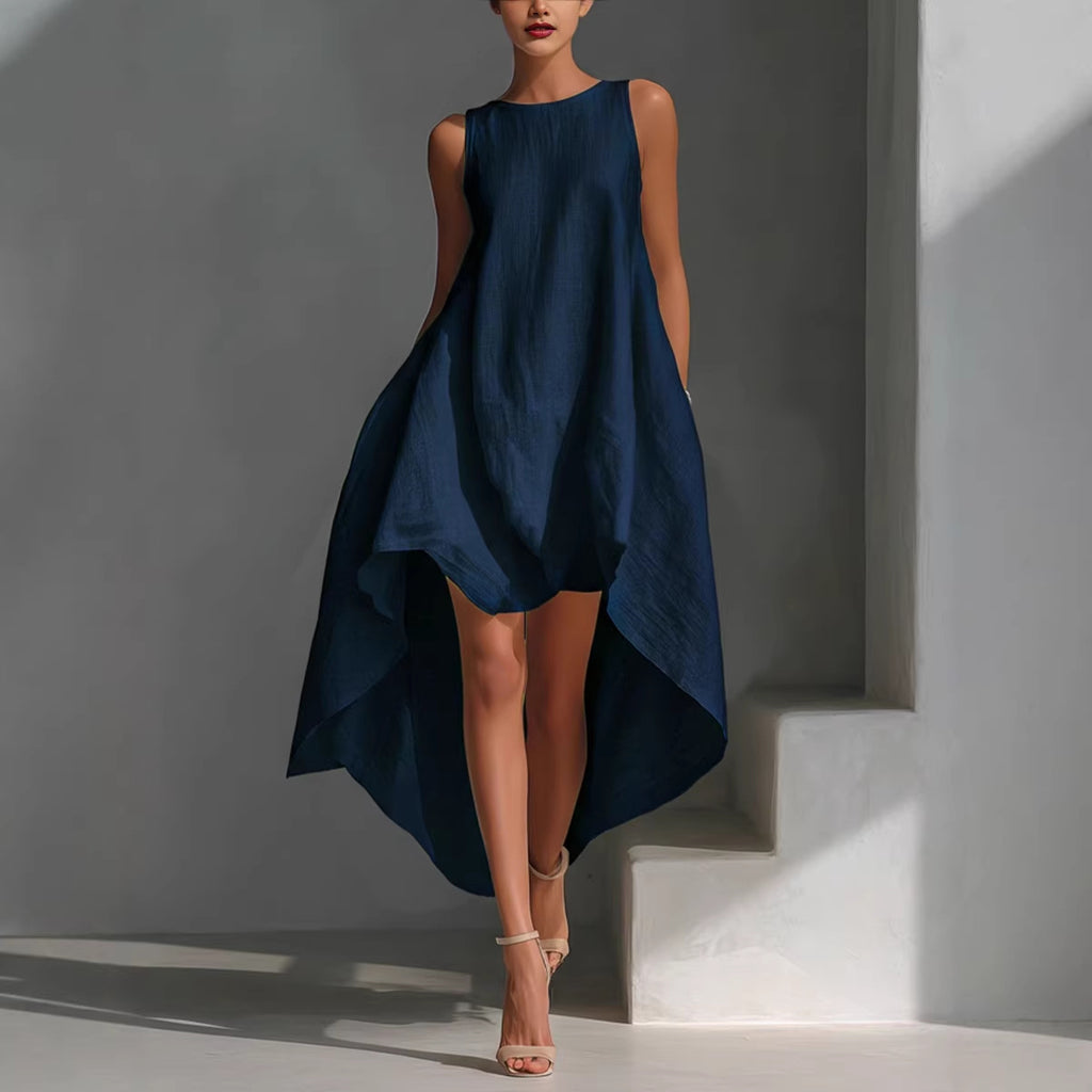 Woman wearing a navy blue dress standing against a gray wall.