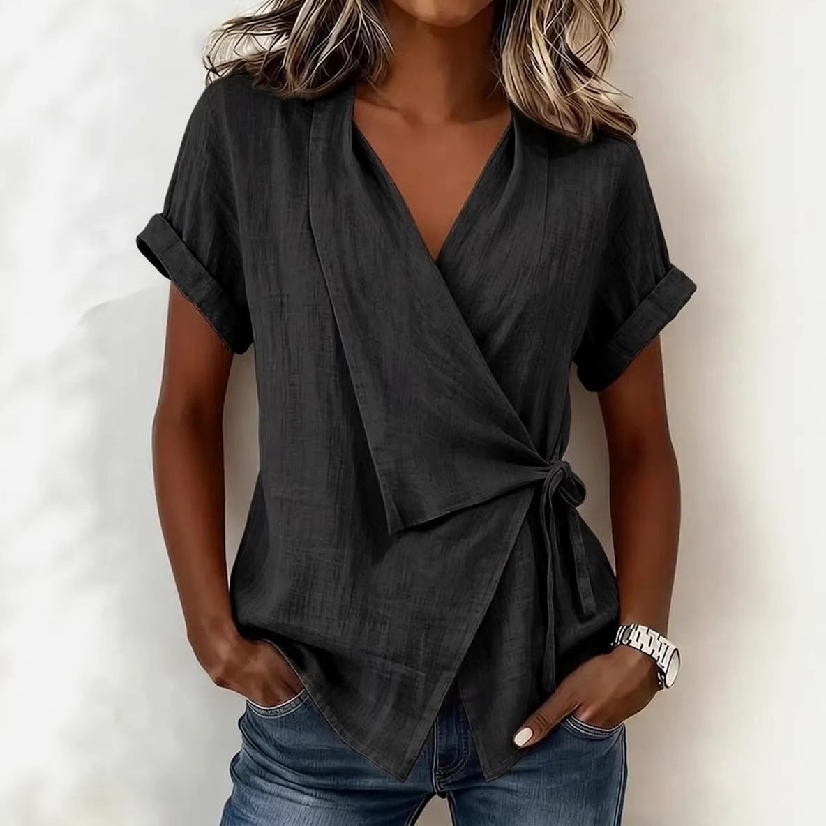Woman wearing a dark gray wrap top with rolled-up sleeves against a white background