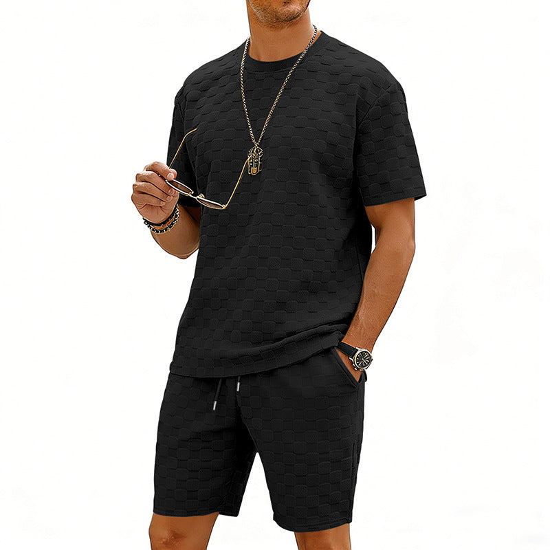 Man wearing a black t-shirt and shorts set with sunglasses on a white background