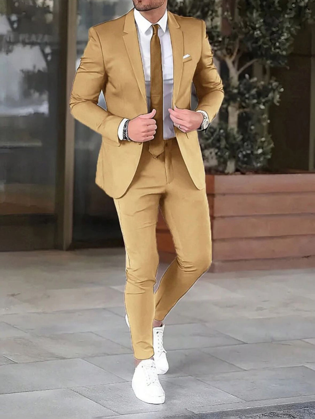 Man wearing a beige suit with white shoes on a city street.