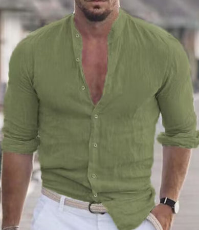 Man wearing a green button-up shirt with rolled-up sleeves, standing outdoors.