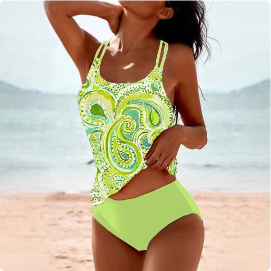 Woman wearing a green and white patterned swimsuit on a beach.