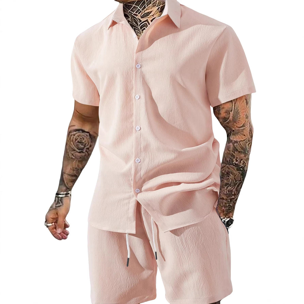 Person wearing a light pink outfit with tattoos on arms against a white background