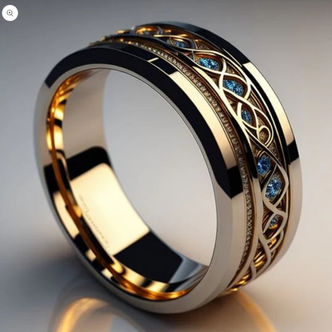 Gold ring with intricate design and blue gemstones on a reflective surface