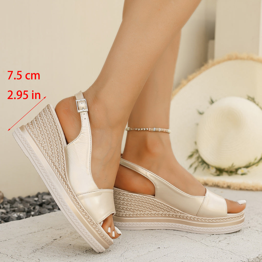 Beige wedge sandals worn by a person with a straw hat in the background