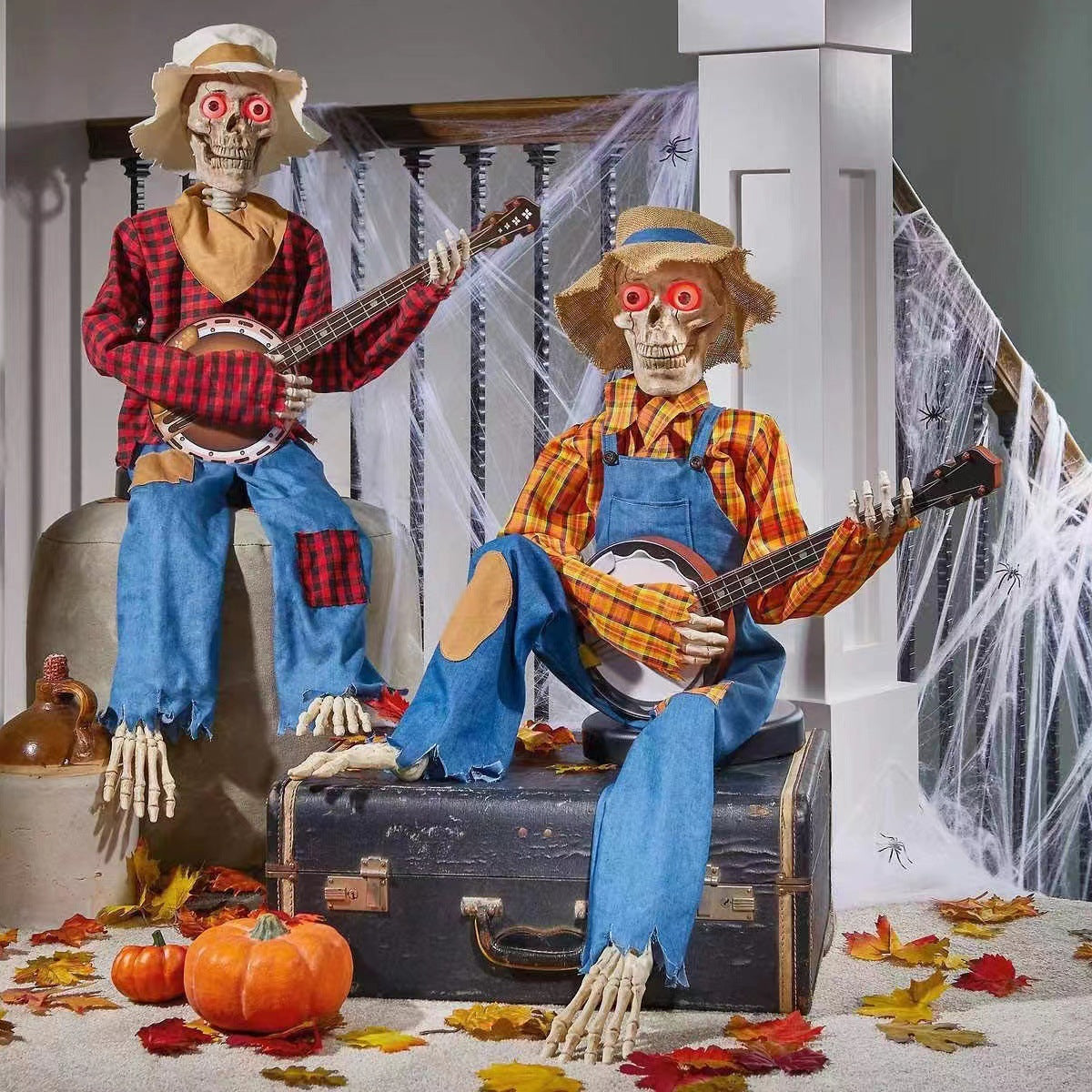 Two skeletons in plaid shirts and overalls playing banjos on a staircase with Halloween decorations.