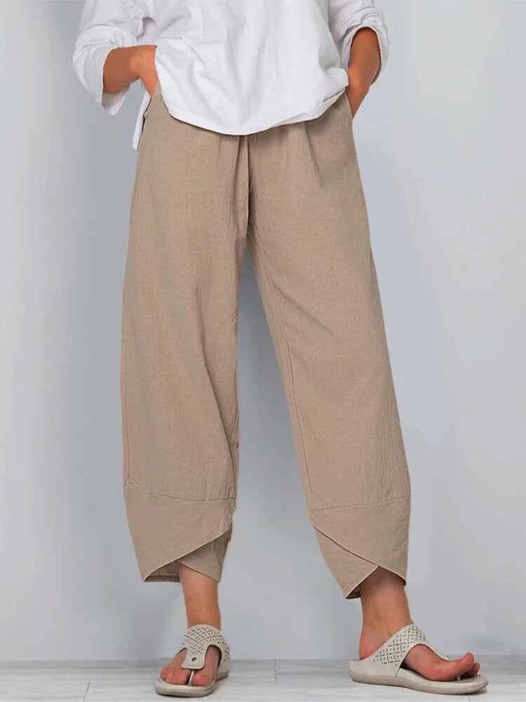 Person wearing beige wide-leg pants and a white shirt on a plain background