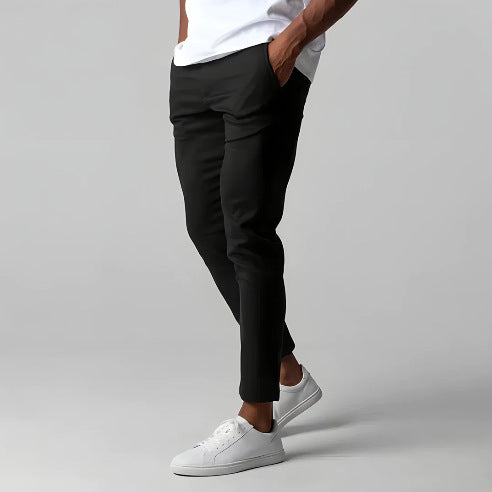 Person wearing black pants and white sneakers on a gray background
