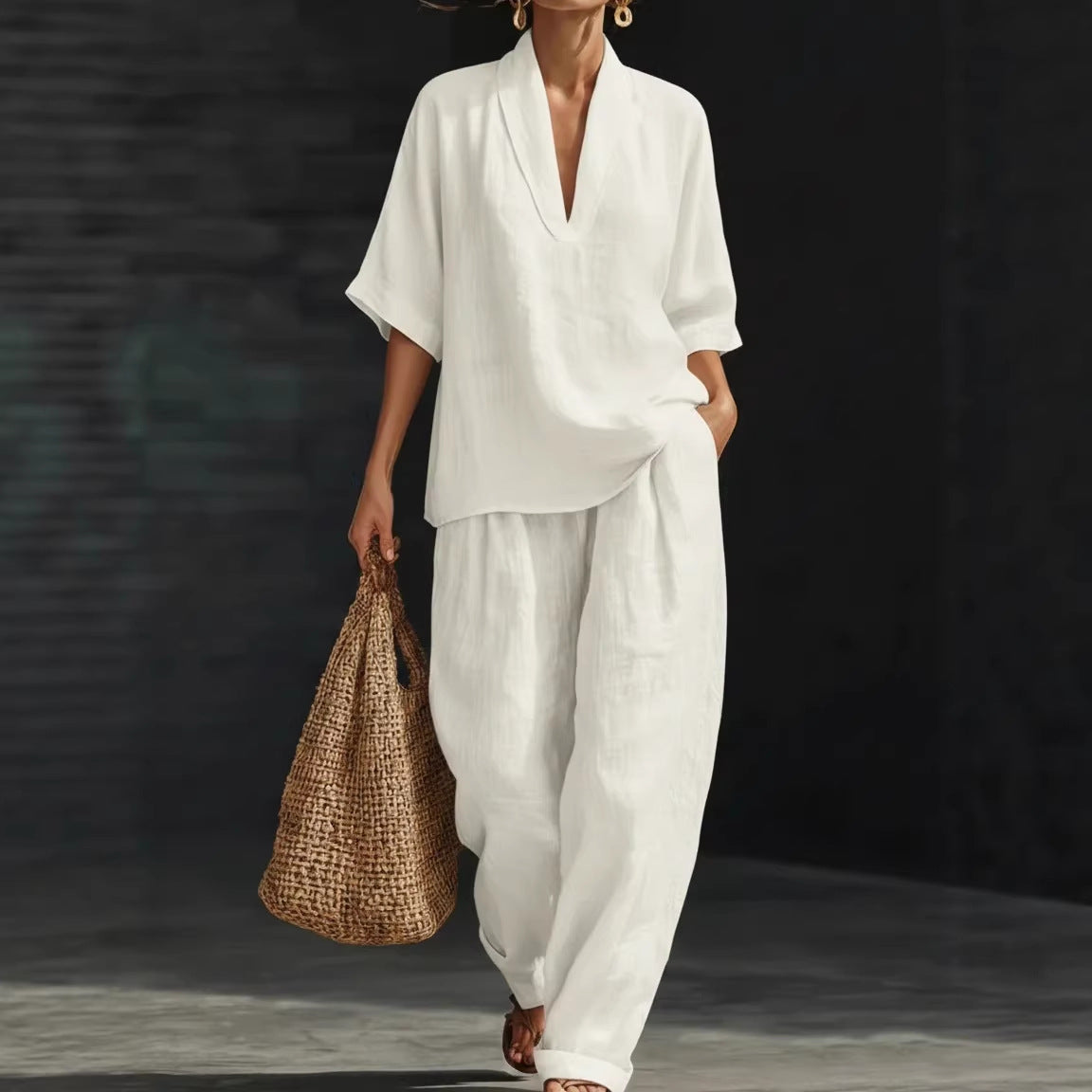 Person wearing a white outfit holding a woven bag against a dark background