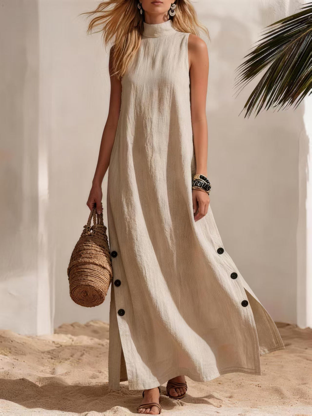 Woman in a long beige dress with black buttons standing on sand with a neutral background