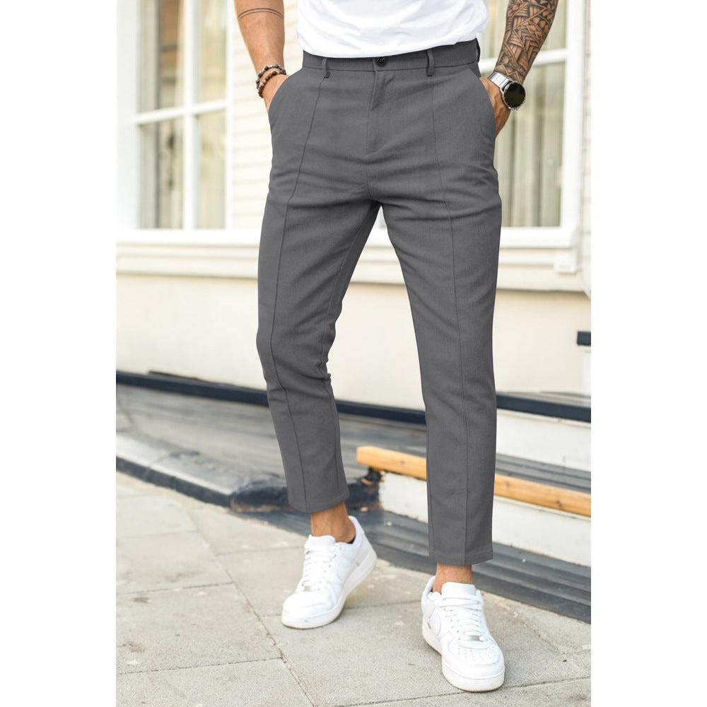 Person wearing gray pants and white sneakers standing on a sidewalk.