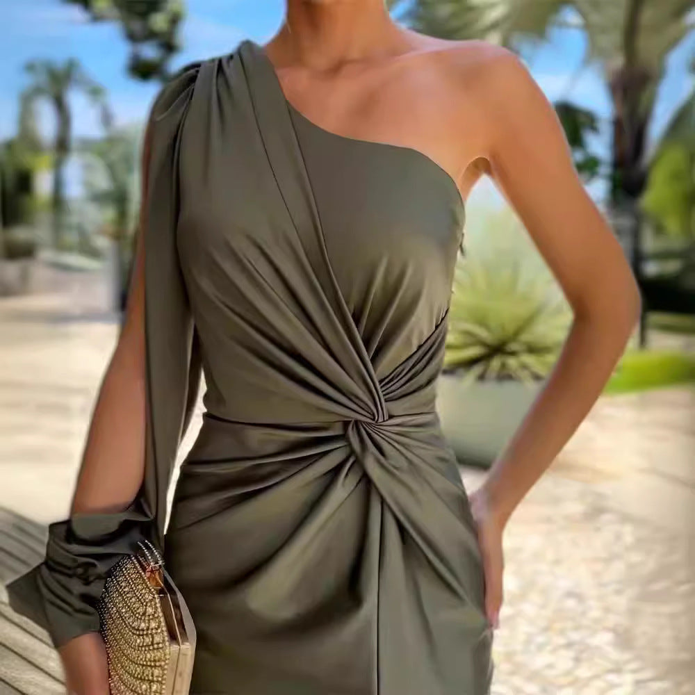 Woman wearing a green one-shoulder dress with a blurred outdoor background