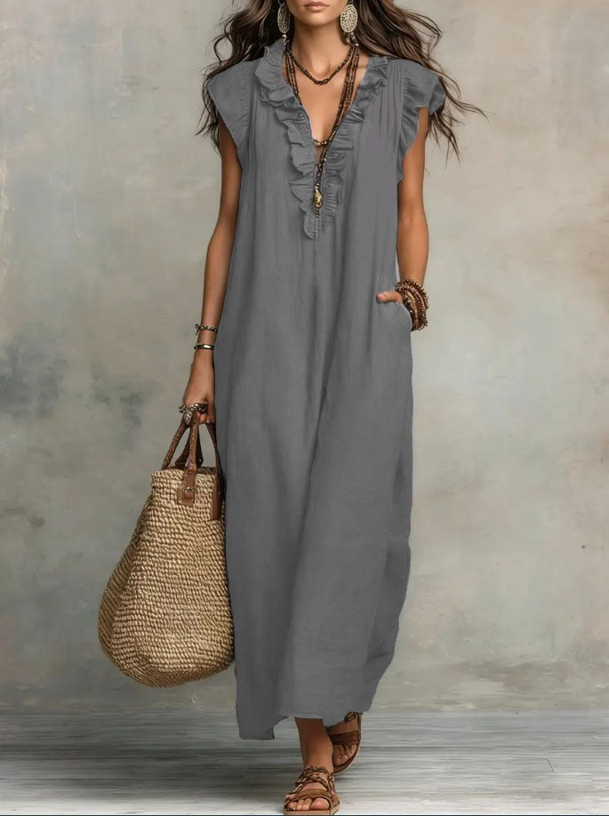 Woman wearing a gray sleeveless dress holding a straw bag against a neutral background