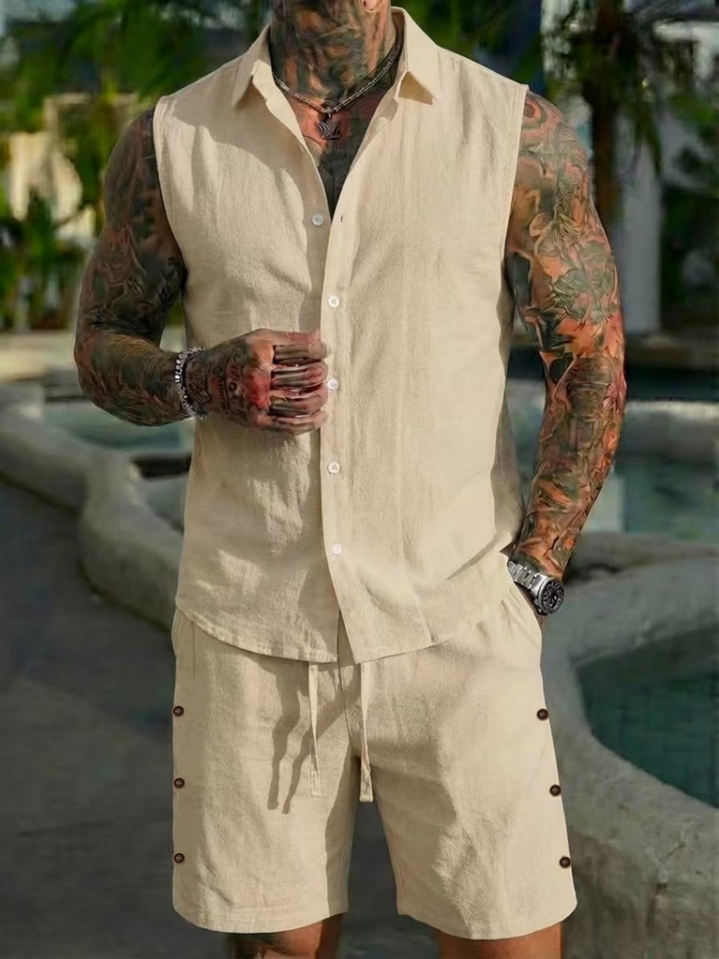 Man wearing a beige linen outfit with tattoos in an outdoor setting