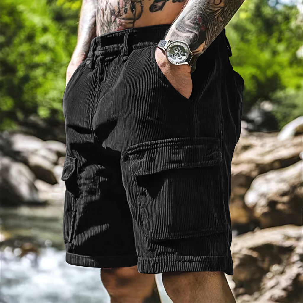 Person wearing black cargo shorts with a blurred natural background