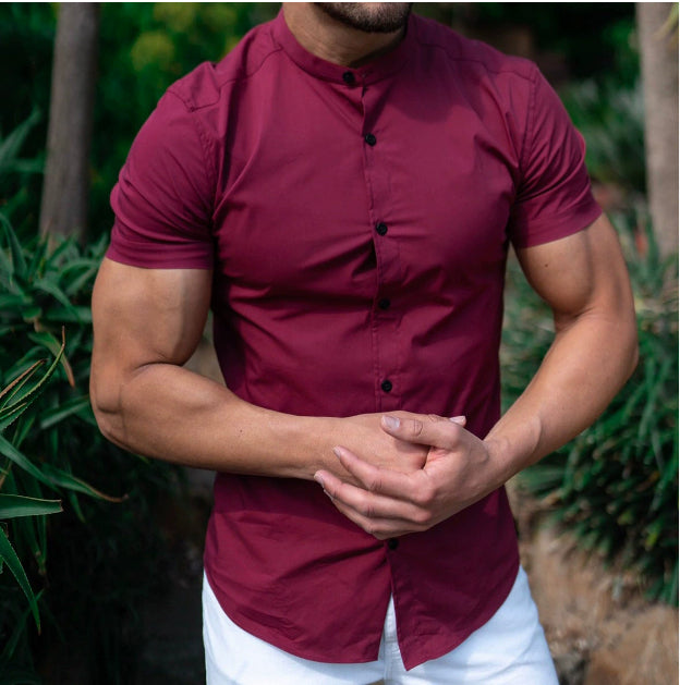 Man wearing a maroon short-sleeve shirt with a blurred natural background