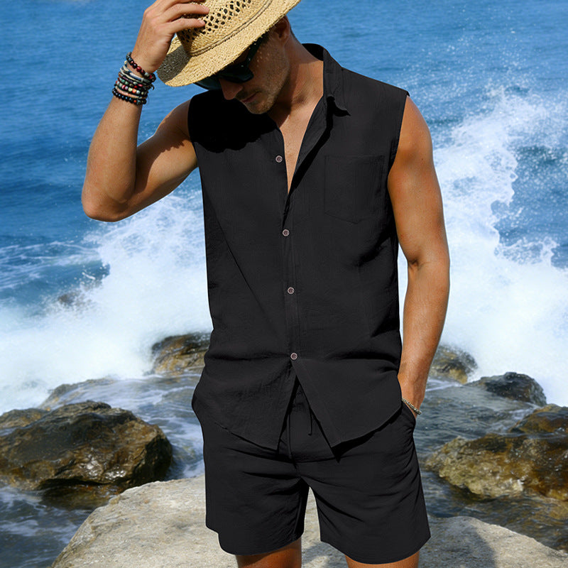 Man wearing a black sleeveless shirt and shorts with a straw hat by the ocean.