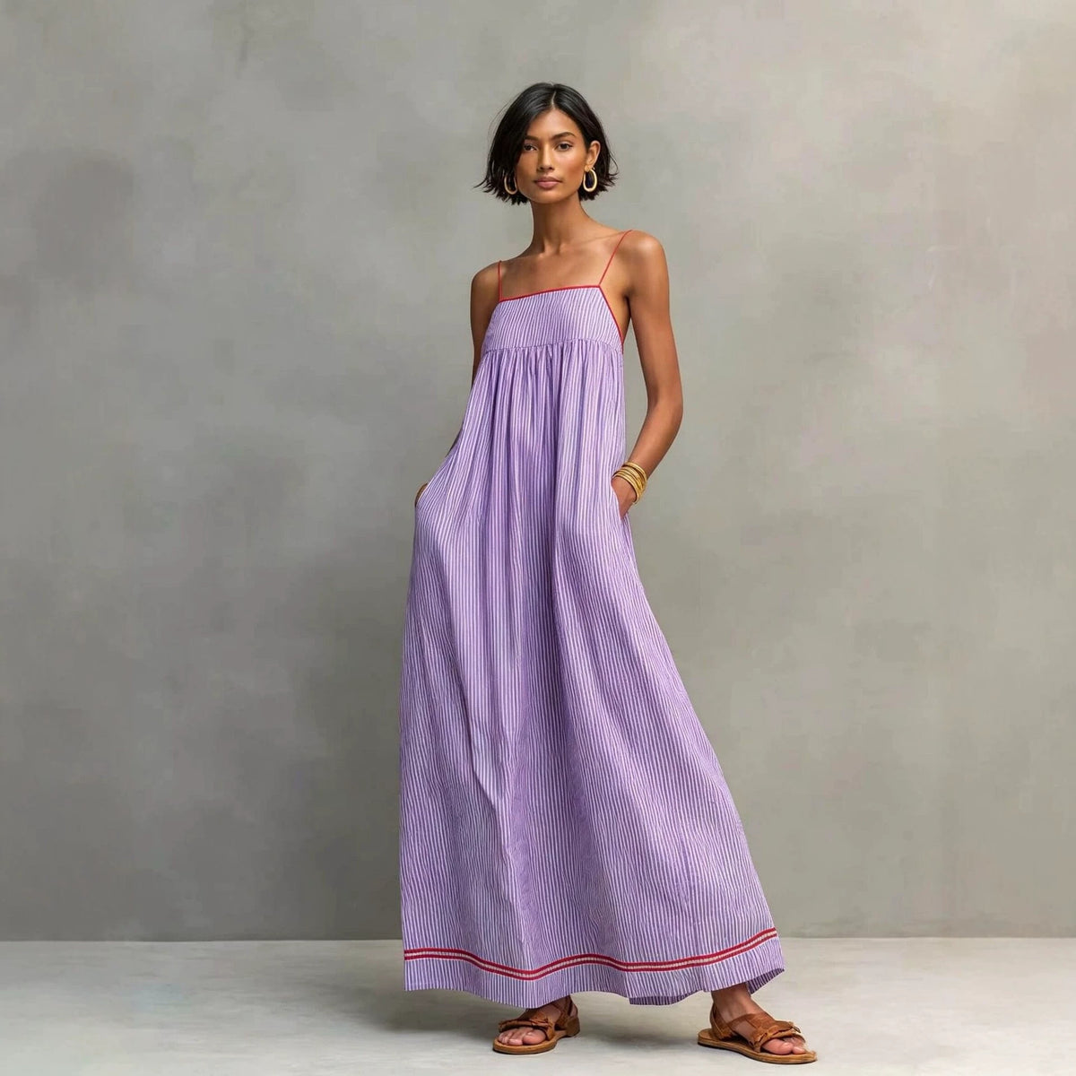 Woman wearing a long purple dress against a gray background