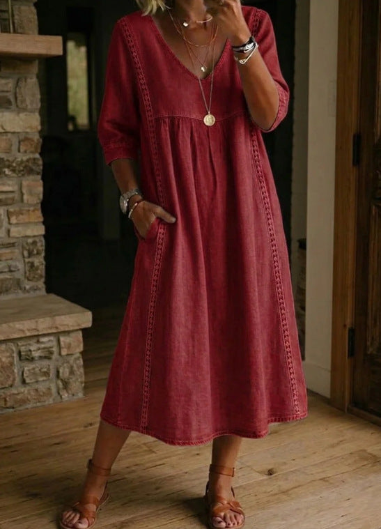 Person wearing a red dress standing in a room with wooden flooring and a stone fireplace.