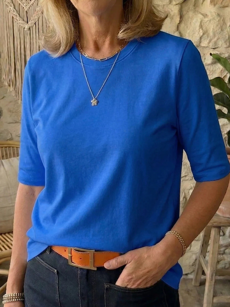Person wearing a blue shirt with a stone wall background